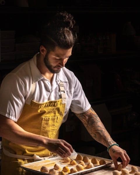 A cook laying filled pasta out on a tray in the store room